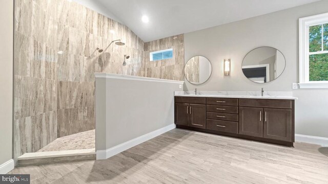 bathroom featuring a tile shower, vanity, hardwood / wood-style flooring, and lofted ceiling