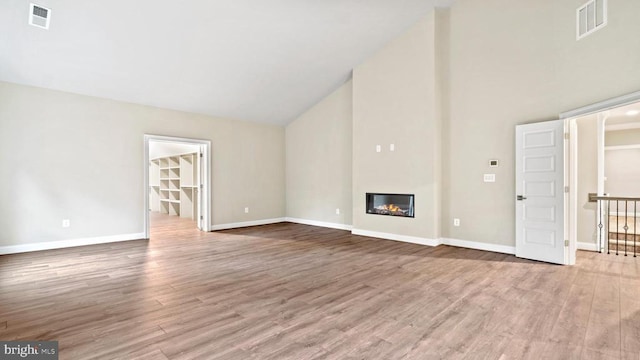 unfurnished living room with high vaulted ceiling and light wood-type flooring