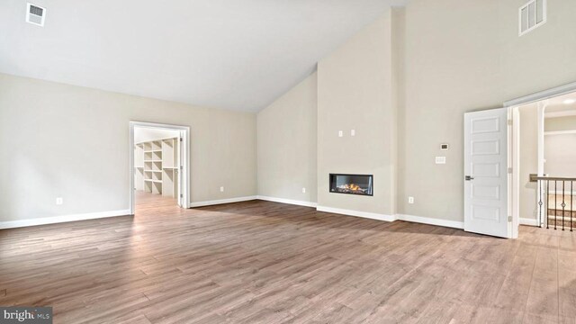 unfurnished living room with high vaulted ceiling and light wood-type flooring