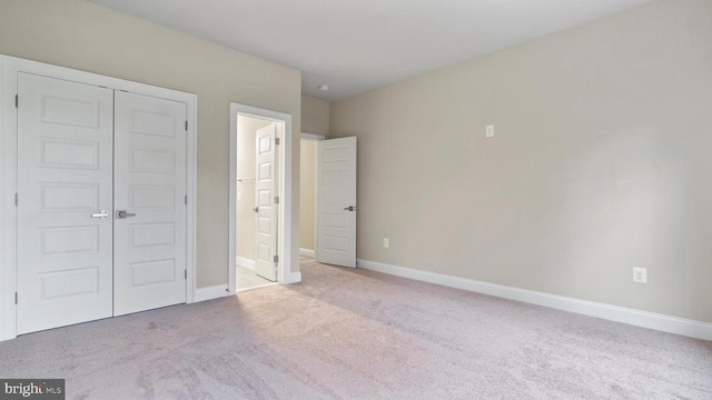 unfurnished bedroom featuring connected bathroom, light carpet, and a closet