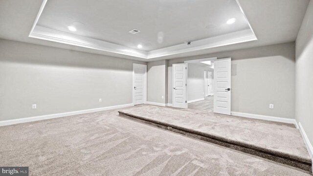 unfurnished bedroom with ornamental molding, a raised ceiling, and carpet flooring