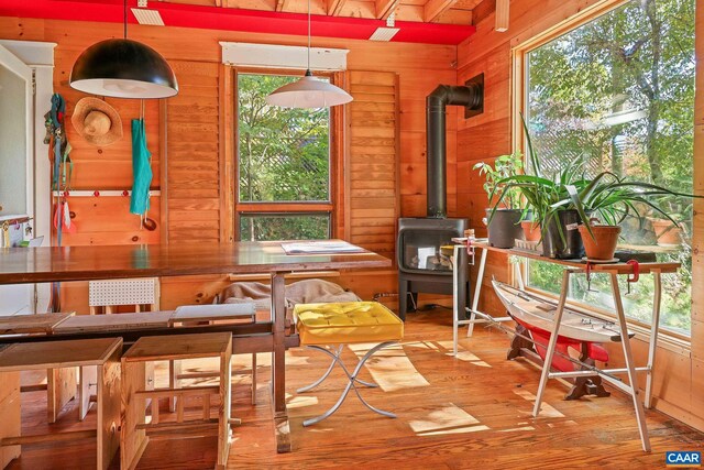 dining space featuring wood-type flooring, a wood stove, wood ceiling, and wooden walls