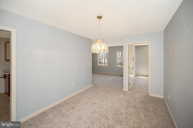 unfurnished room featuring light colored carpet and baseboards