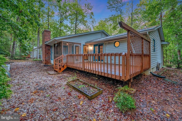 rear view of property with a wooden deck and a sunroom