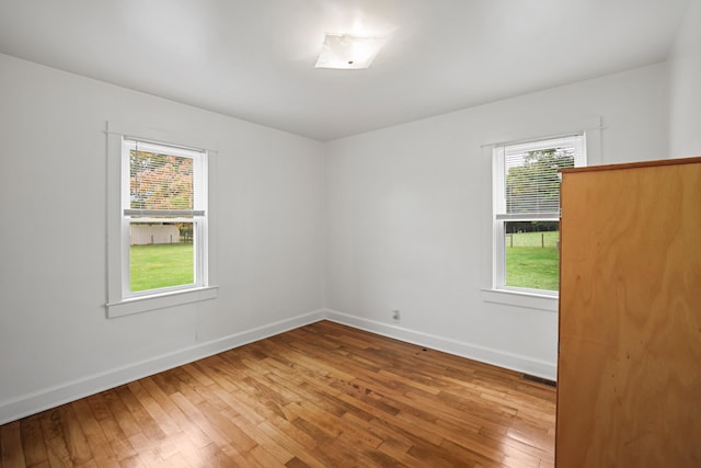 unfurnished room with wood-type flooring and a healthy amount of sunlight