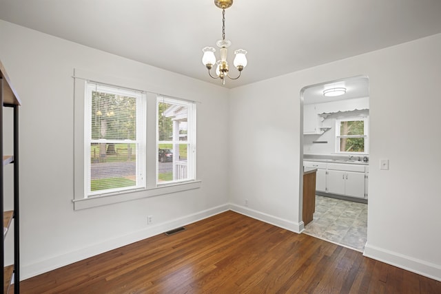 unfurnished dining area featuring hardwood / wood-style flooring and a chandelier