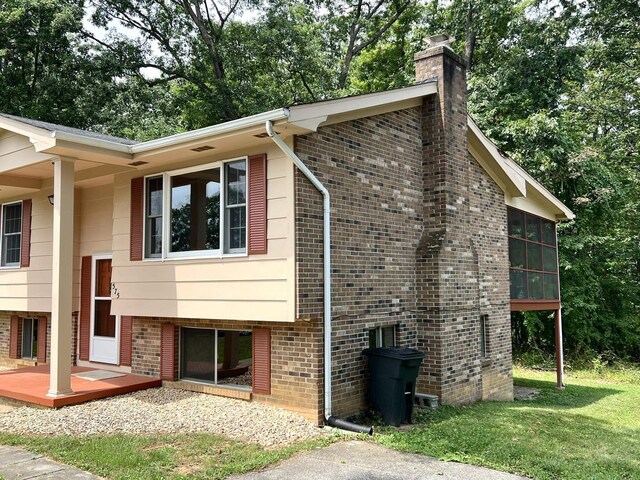 view of side of property featuring a lawn and a sunroom