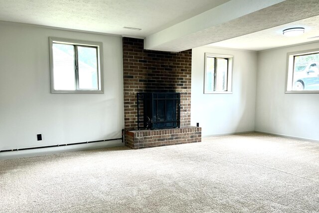 unfurnished living room featuring baseboard heating, a brick fireplace, a textured ceiling, and carpet