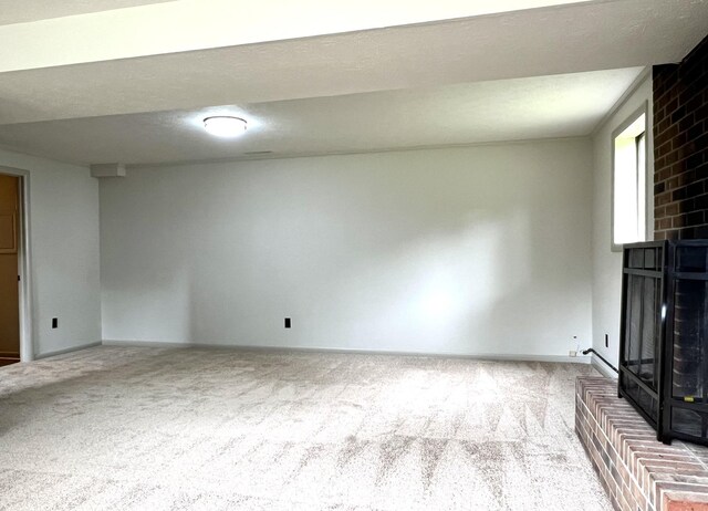 unfurnished living room with a brick fireplace, light carpet, and a textured ceiling