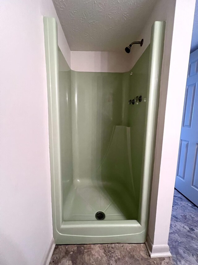 bathroom with a textured ceiling and a shower