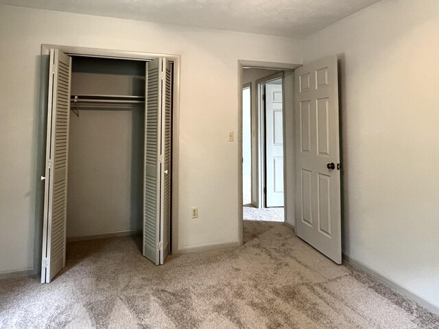 unfurnished bedroom featuring light carpet and a closet