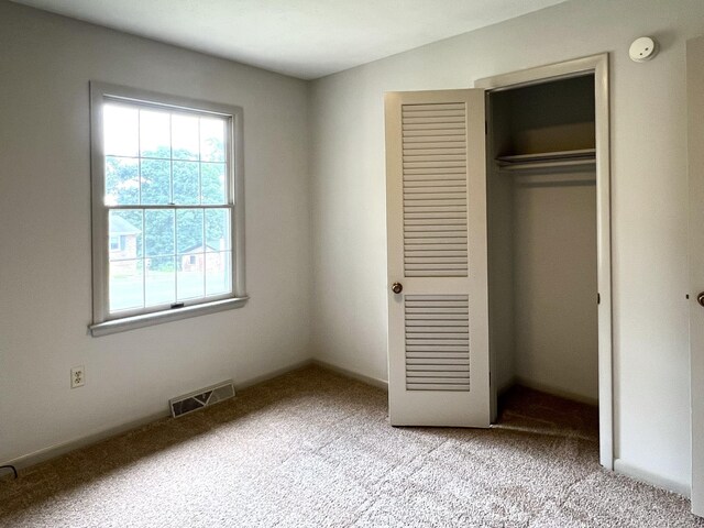 unfurnished bedroom featuring light colored carpet and a closet