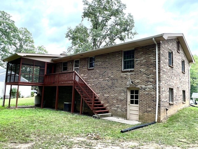 back of property with a yard, a sunroom, and a deck