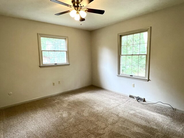 unfurnished room featuring plenty of natural light, carpet, and ceiling fan