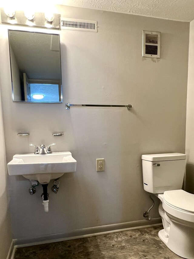 bathroom with sink, a textured ceiling, and toilet