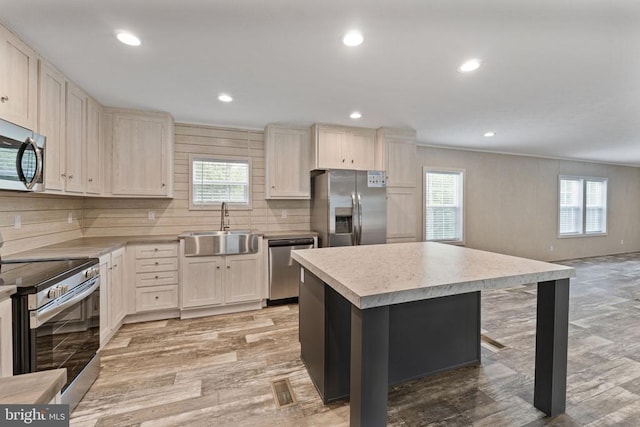 kitchen with a breakfast bar, sink, appliances with stainless steel finishes, plenty of natural light, and a kitchen island