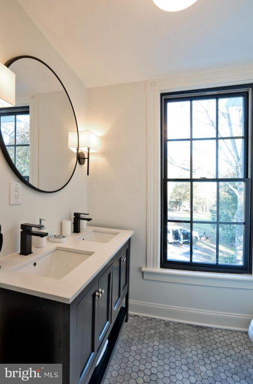 bathroom featuring lofted ceiling, double vanity, a sink, and baseboards