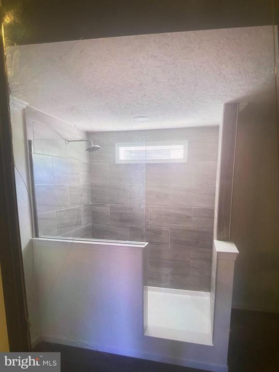 bathroom with a walk in shower and a textured ceiling