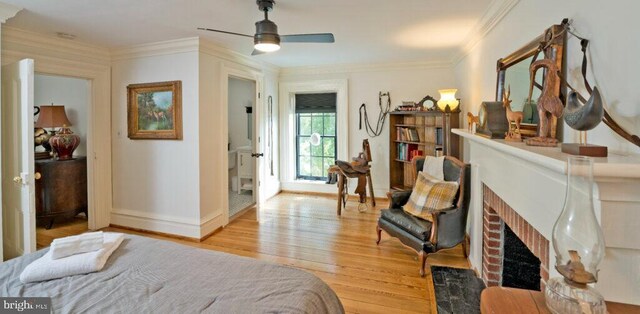 bedroom with a fireplace, baseboards, crown molding, and light wood finished floors