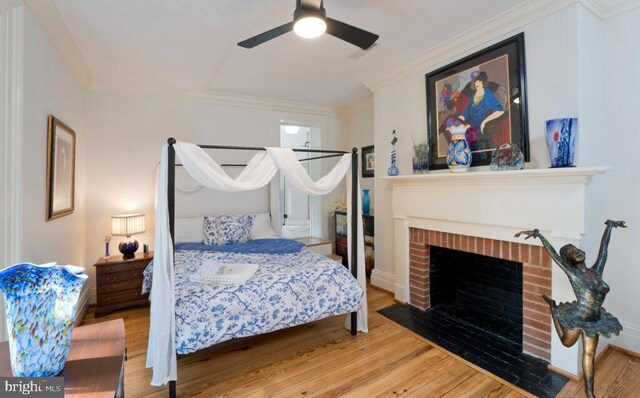 bedroom with ornamental molding, a fireplace, and wood finished floors