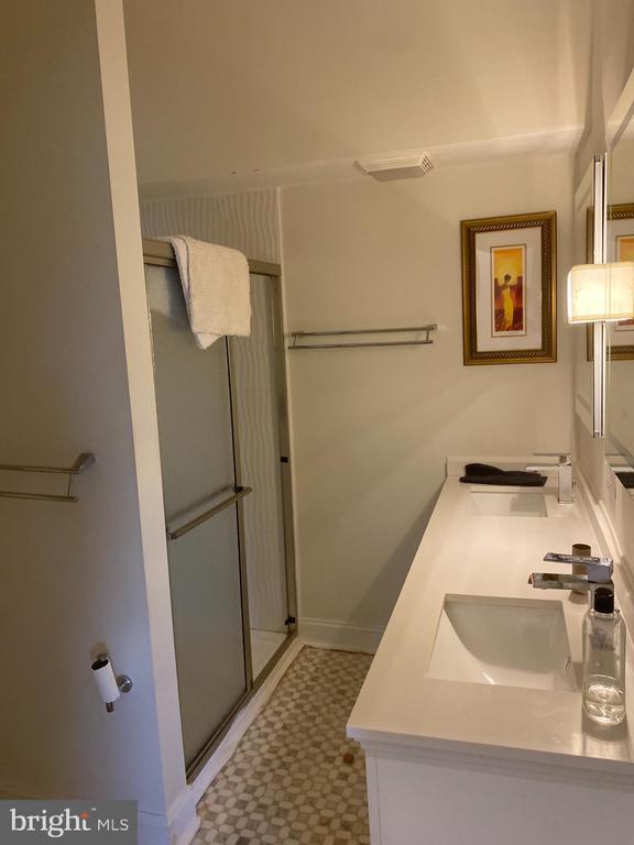 full bathroom featuring double vanity, visible vents, tile patterned floors, a shower stall, and a sink