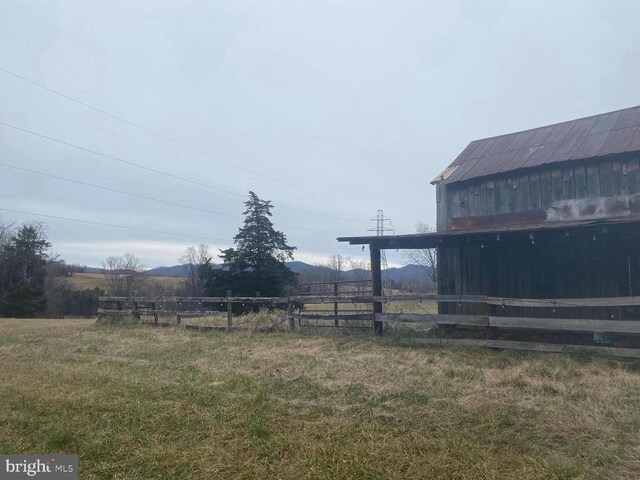 view of yard featuring a barn, a rural view, fence, and an outdoor structure