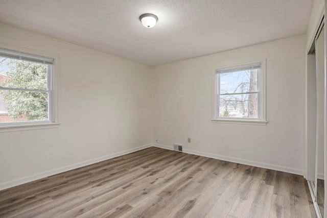 unfurnished room featuring light hardwood / wood-style floors and a textured ceiling