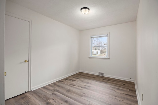 empty room with wood-type flooring and a textured ceiling