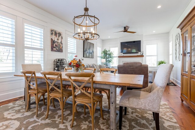 dining area with ceiling fan with notable chandelier and hardwood / wood-style floors