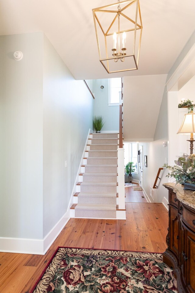 staircase featuring hardwood / wood-style flooring and a notable chandelier