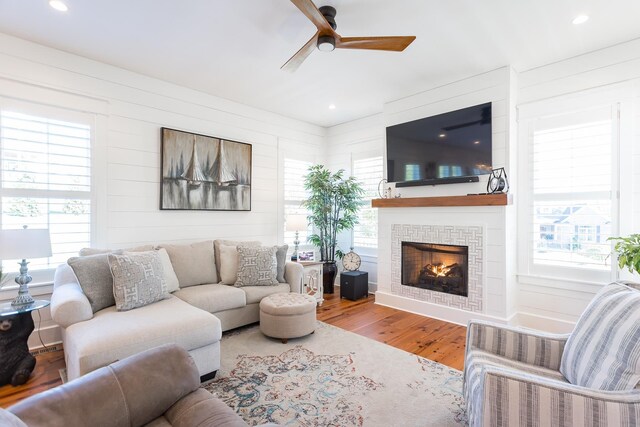 living room featuring hardwood / wood-style flooring, ceiling fan, plenty of natural light, and a fireplace