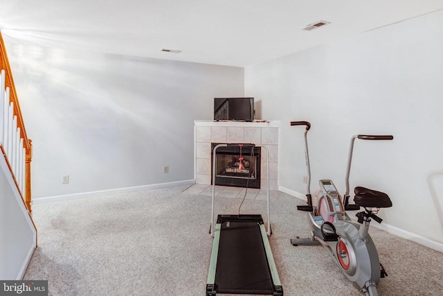 exercise room with baseboards, visible vents, carpet floors, and a tile fireplace