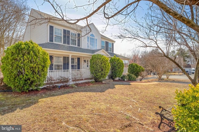 view of front of home with a porch, a shingled roof, and a front yard