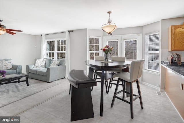 dining area featuring visible vents, a healthy amount of sunlight, baseboards, and a ceiling fan