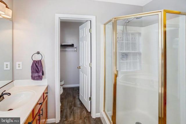 full bathroom featuring vanity, toilet, wood finished floors, and a stall shower