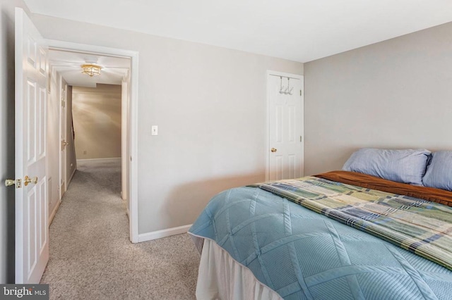 bedroom with a closet, light colored carpet, and baseboards