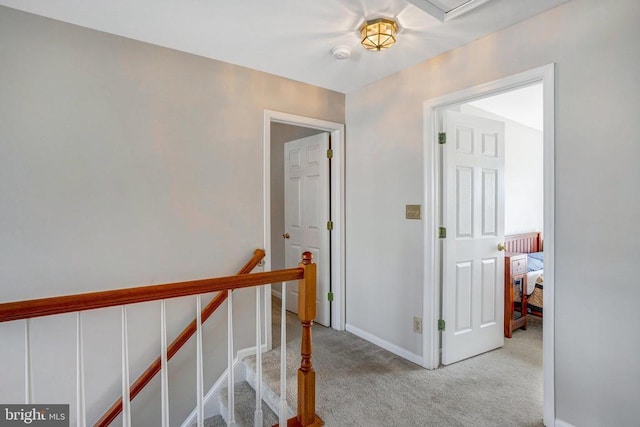 corridor with baseboards, an upstairs landing, and carpet flooring