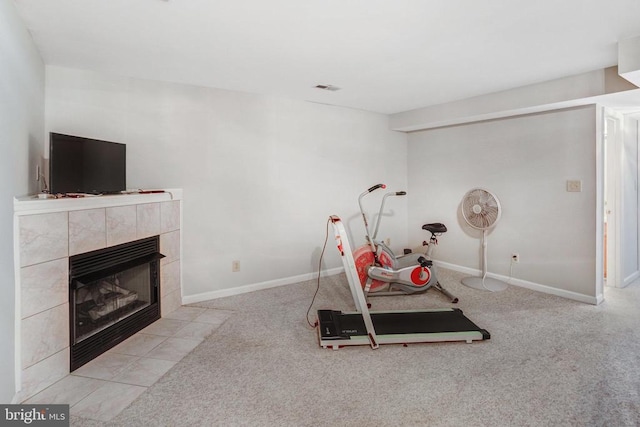 exercise area featuring a tiled fireplace, carpet, baseboards, and visible vents