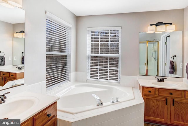 full bathroom with a stall shower, a garden tub, and a sink