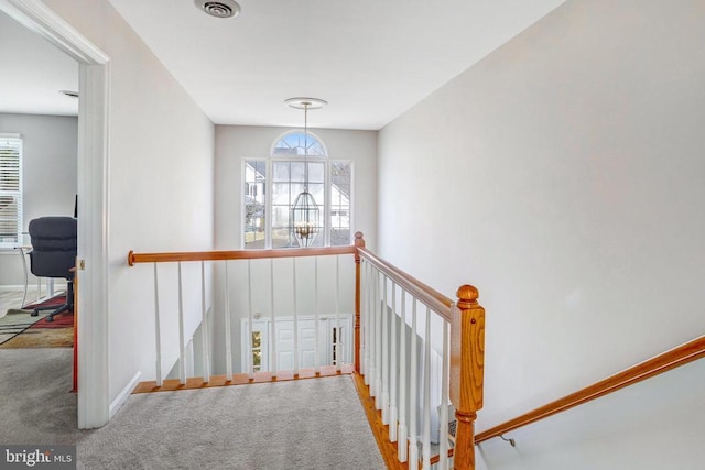 stairway featuring plenty of natural light, carpet flooring, baseboards, and visible vents