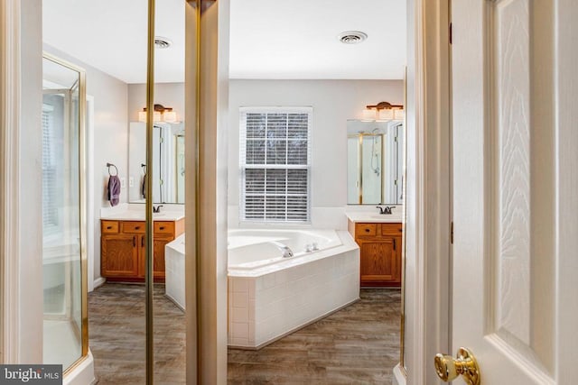 bathroom with vanity, a bath, wood finished floors, and visible vents