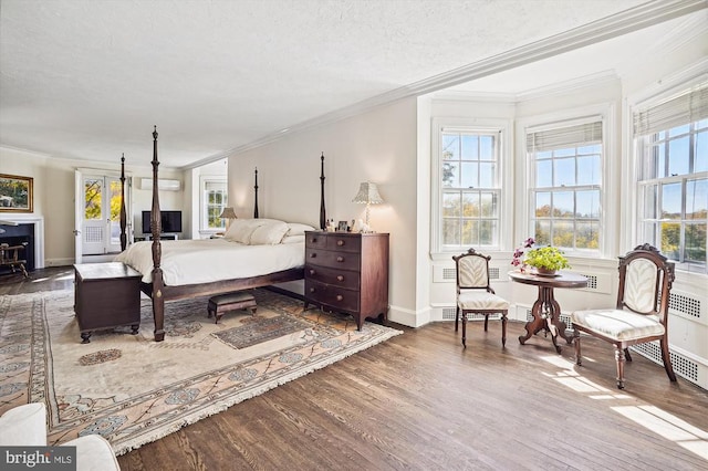 bedroom featuring a wall mounted air conditioner, hardwood / wood-style floors, a textured ceiling, and crown molding