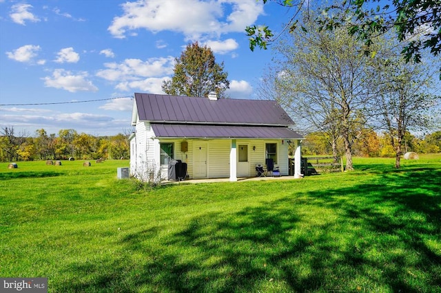 view of outdoor structure with a yard, central air condition unit, and covered porch