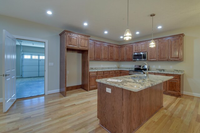 kitchen with baseboards, appliances with stainless steel finishes, a sink, and light wood-style flooring