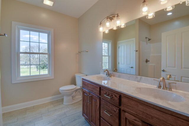 bathroom featuring baseboards, a sink, and a healthy amount of sunlight