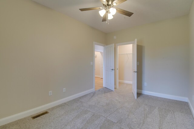 unfurnished bedroom featuring baseboards, visible vents, light colored carpet, and ceiling fan