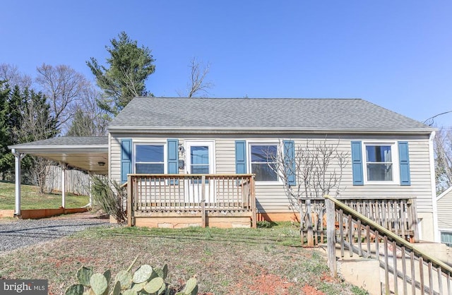 view of front of property with a carport, driveway, and roof with shingles