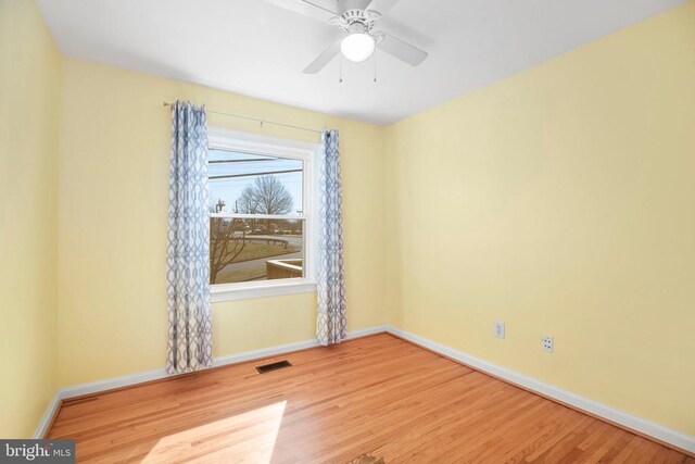 spare room featuring ceiling fan, baseboards, and wood finished floors