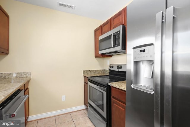 kitchen with light stone counters, baseboards, visible vents, light tile patterned flooring, and stainless steel appliances