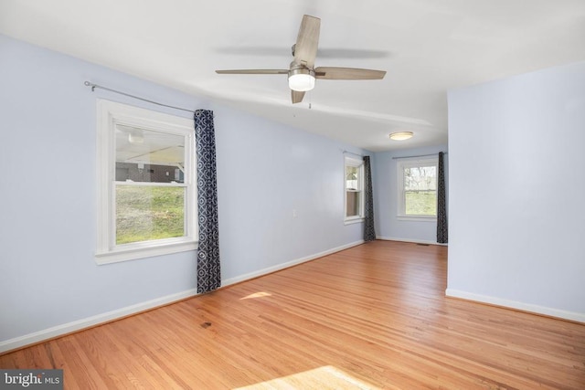 spare room with baseboards, wood finished floors, and a ceiling fan